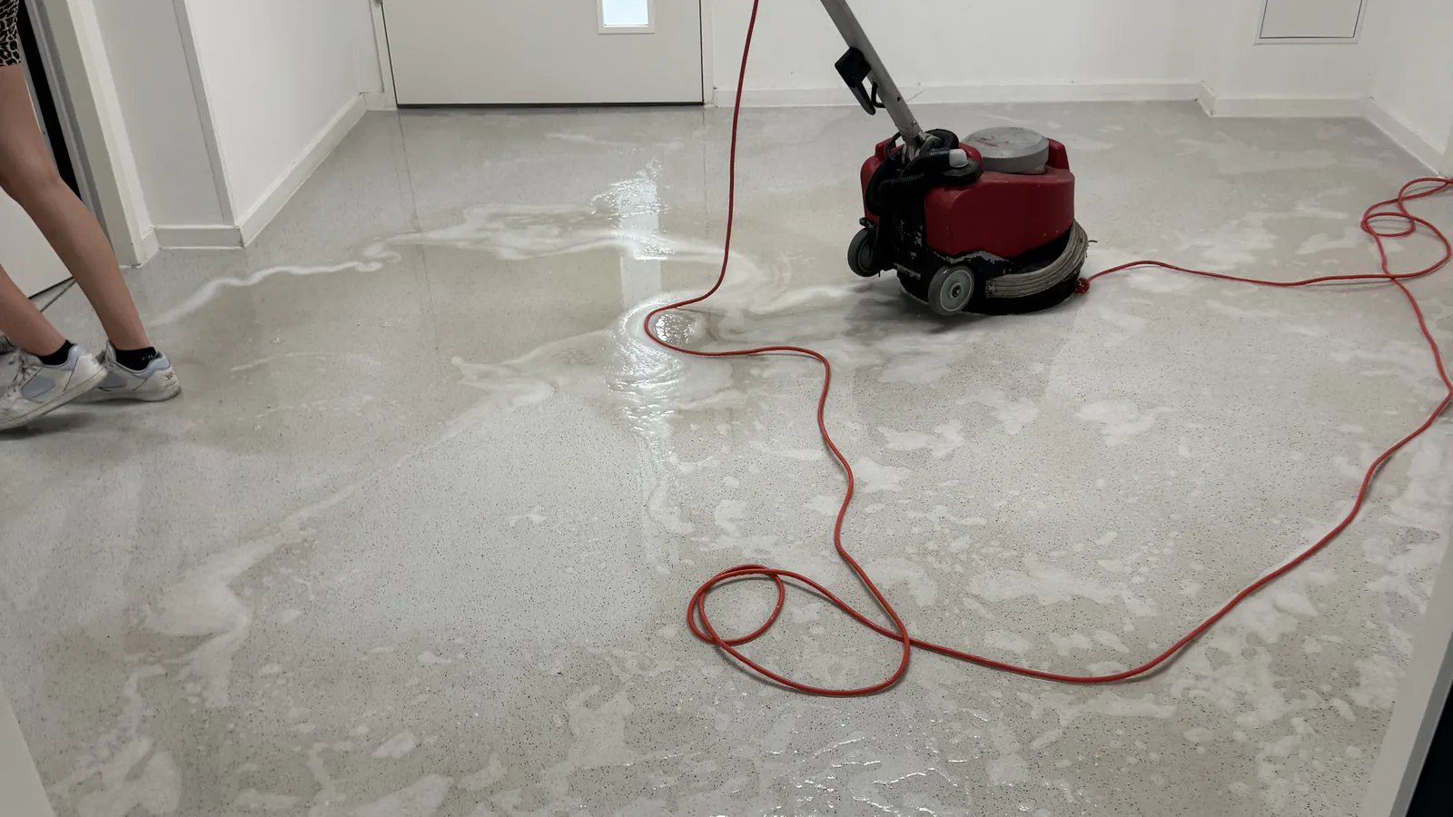 Mitarbeiter mit Einscheibenmaschine bei der maschinellen Bodenreinigung